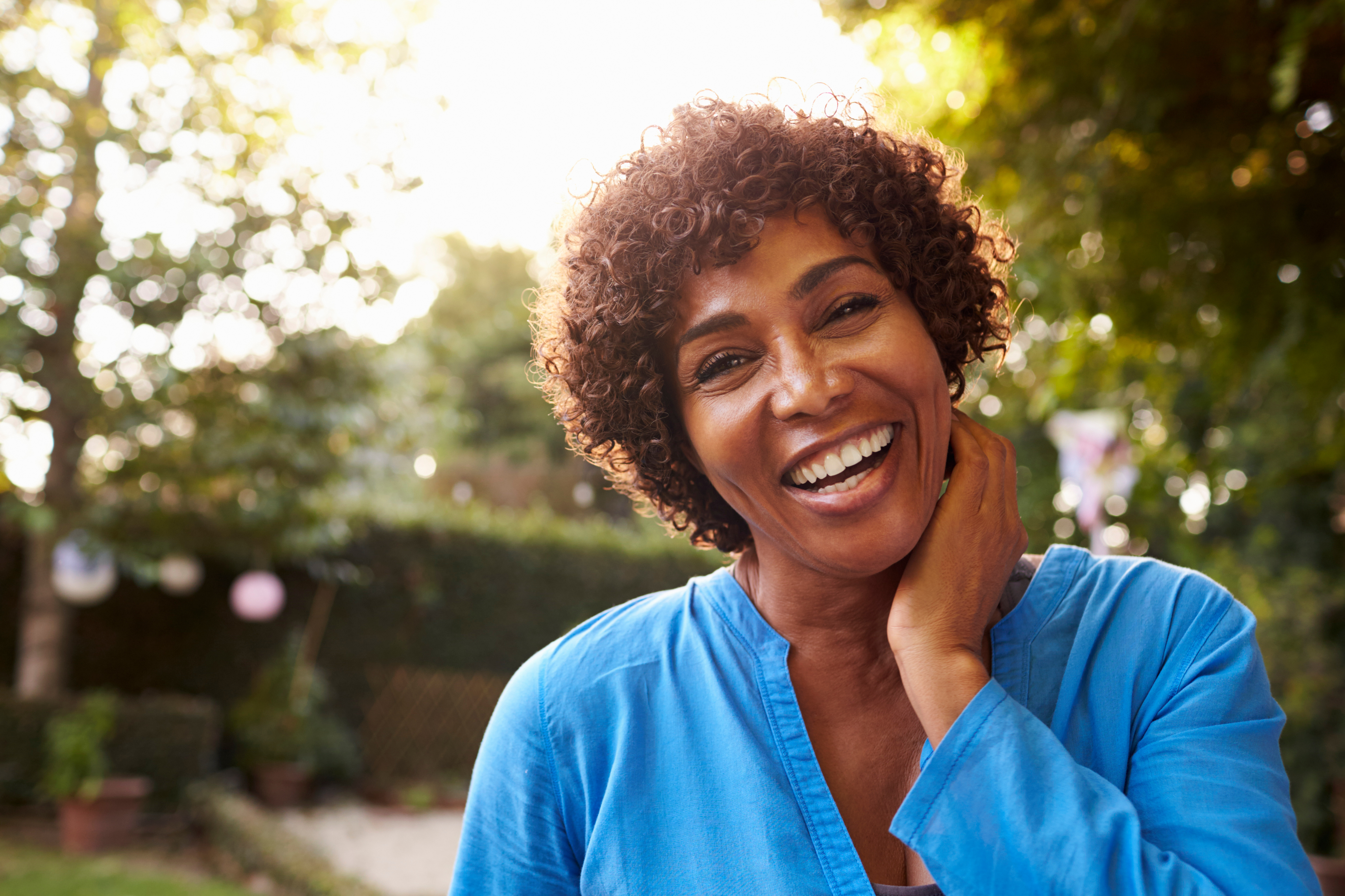 A smiling woman stands in a garden