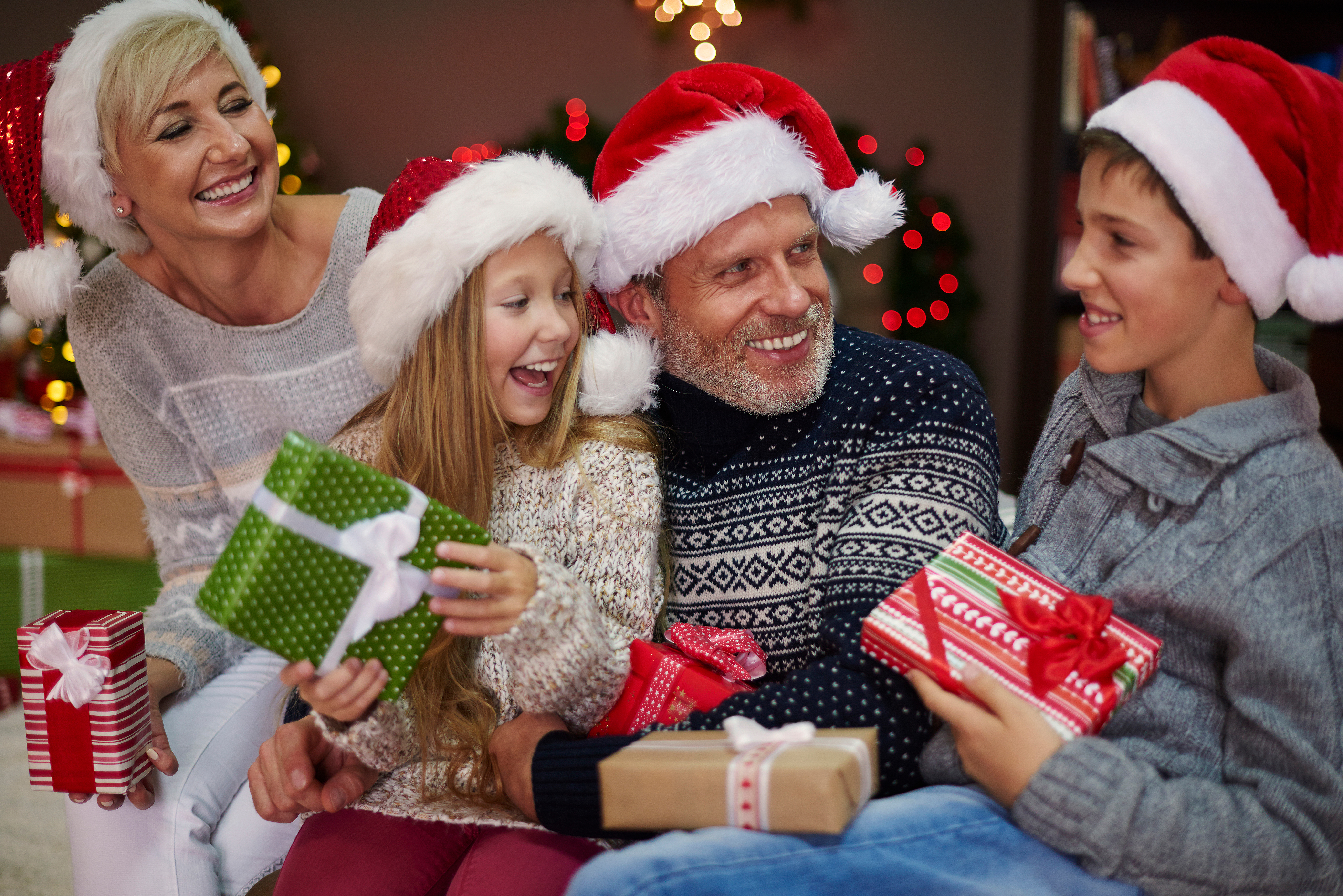 A family opening gifts they bought with money they set aside in their Christmas Club Savings Account.
