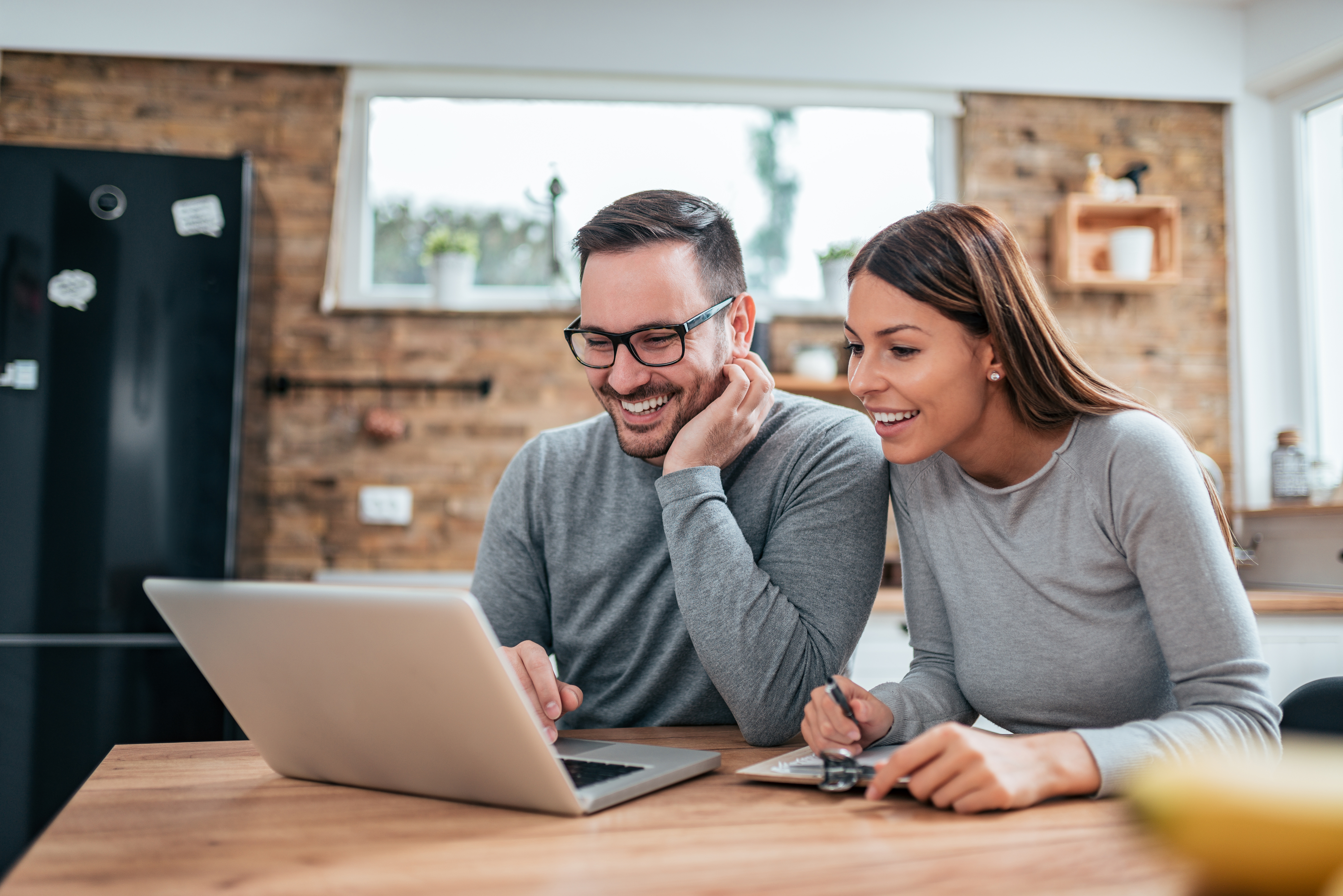 MAN AND WOMAN SMILING LOOKING AT LAPTOP