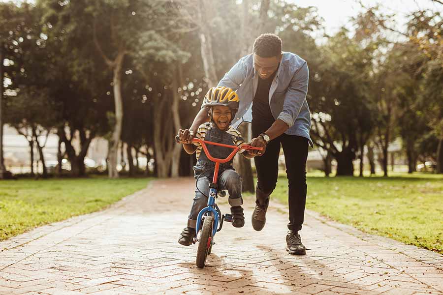 child riding bicycle with father smiling